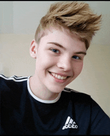 a young boy wearing a black adidas shirt smiles for the camera