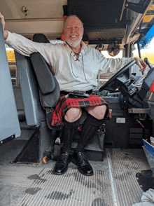 a man in a kilt sits in the driver 's seat of a school bus