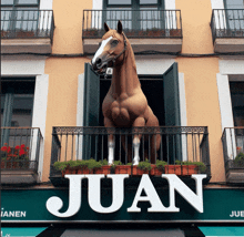 a statue of a horse on a balcony with the word juan above it