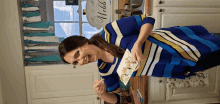 a woman in a blue and white striped shirt is holding a plate of food in front of a welcome sign