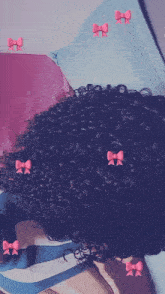 a woman with curly hair is laying on a bed with pink bows on her hair