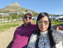 a man and a woman pose for a photo in front of a mountain