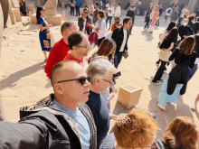 a group of people are gathered in a plaza and one of them is wearing a blue shirt