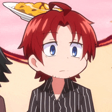 a boy with red hair has a plate of food on top of his head