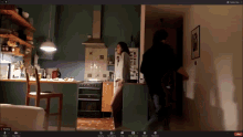 a computer screen shows a woman standing in a kitchen and a man standing behind her