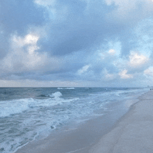 a beach with a cloudy sky and waves crashing against the sand