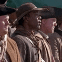 a group of men are standing next to each other in a line wearing hats .