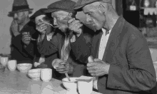 a group of men are eating from bowls and spoons