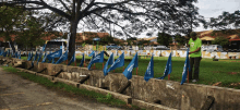 a man in a green shirt stands next to a row of blue flags that say ' merdeka '