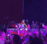 a crowd of people are taking pictures of a man on stage with their cell phones