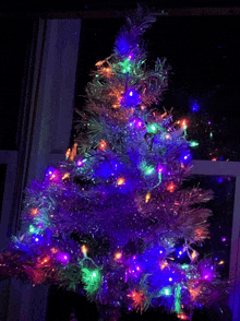 a white christmas tree with purple and green lights