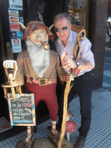 a man stands next to a statue of a gnome with a sign that says " si crees en la magia "