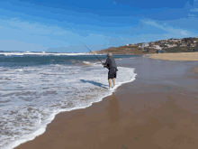 a man is fishing on a sandy beach near the water