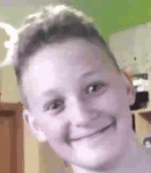 a close up of a young boy 's face smiling in a room .