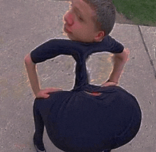 a young boy is squatting down on a sidewalk with a very large butt .