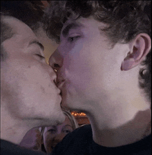 two men kissing in front of a crowd of people