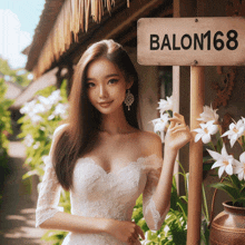 a woman in a white dress stands in front of a sign that reads balon168