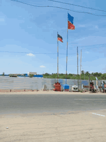 a red white and blue flag is flying in the wind near a body of water