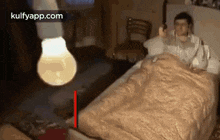 a man is laying in bed with a light bulb hanging over him .