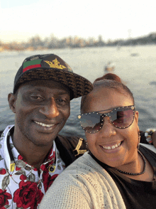 a man wearing a hat and a woman wearing sunglasses pose for a photo