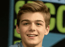 a young man is smiling in front of a sign that says cc