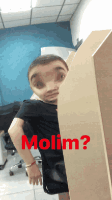 a man in a black shirt is behind a cubicle with the word molim written in red