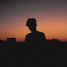 a silhouette of a person in front of a sunset