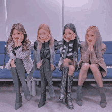 four girls are sitting on a blue bench with their hands on their faces