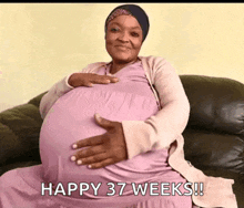 a pregnant woman is sitting on a couch with her hands on her belly and the words happy 37 weeks