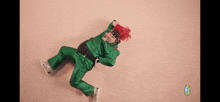 a man with red hair and a green suit is laying on the ground