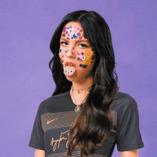 a woman with stickers on her face is wearing a shirt that says taylor swift