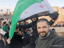 a man holding a flag with the date 13/12/2024 on the bottom right