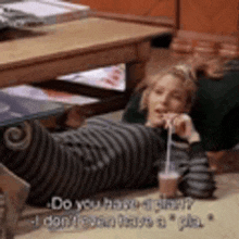 a woman is laying on the floor drinking from a straw and talking to someone .