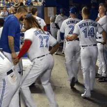 a group of baseball players are standing in a dugout and one of them has the number 14 on his back