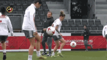 a group of female soccer players are practicing on a field in front of a banner that says belgian football