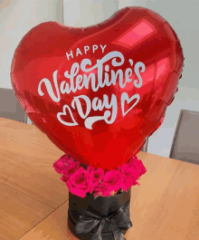 a heart shaped valentine 's day balloon is sitting on top of a box of pink roses