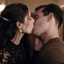 a man and woman are kissing and the woman is wearing a black lace top