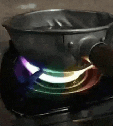 a pot is cooking on a stove with a rainbow colored flame .