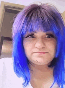 a woman with blue and purple hair is making a face