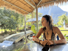 a woman in a bikini sits at a table with a phone