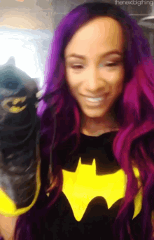 a woman with purple hair is wearing a batman costume and smiling