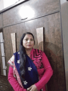 a woman standing in front of a wardrobe wearing a pink top and a blue scarf