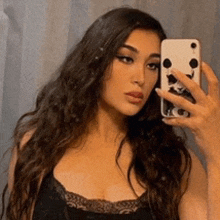 a woman with long hair is taking a selfie with her phone .