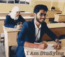 a man is sitting at a desk in a classroom with the words " i am studying " written on the bottom