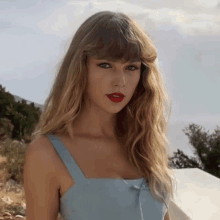 a woman with blonde hair and red lipstick is wearing a blue tank top