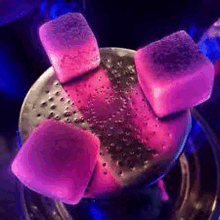 a close up of a hookah with purple charcoal cubes on it .