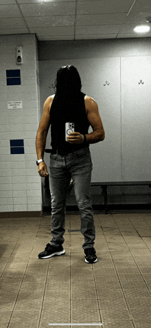 a man taking a selfie in a locker room with a sign that says no smoking