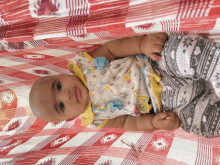 a baby is laying on a red and white blanket