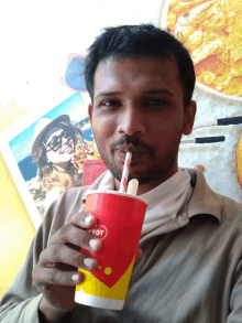 a man drinking from a red and yellow cup that says hot