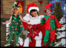 a woman in a santa hat is surrounded by two children dressed in christmas costumes